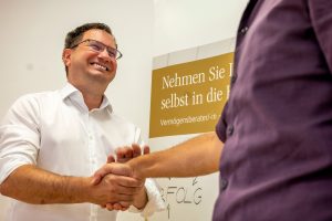 Markus Langegger lächelt und schüttelt einem Kunden die Hand während eines Beratungsgesprächs über Vermögensberatung